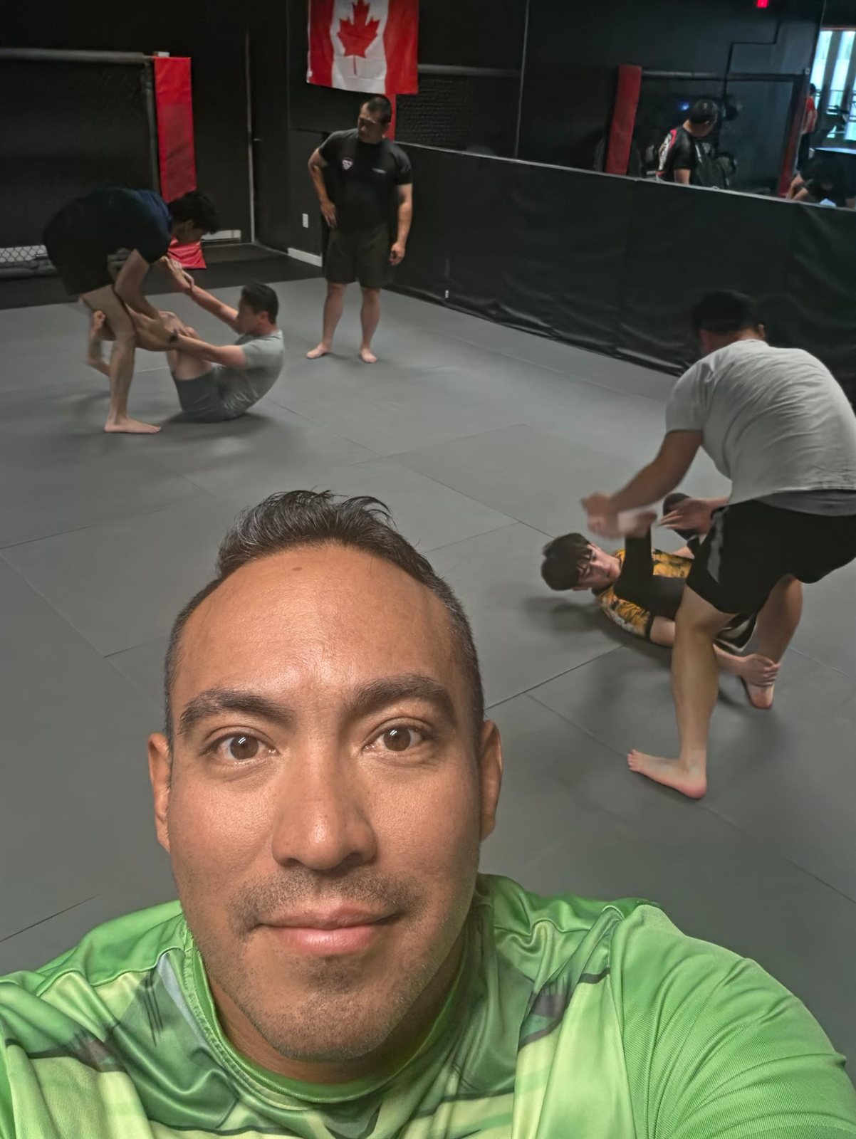 A coach's selfie with students training on the mats behind him